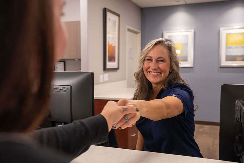 staff member helping patient at the front desk of the dental center