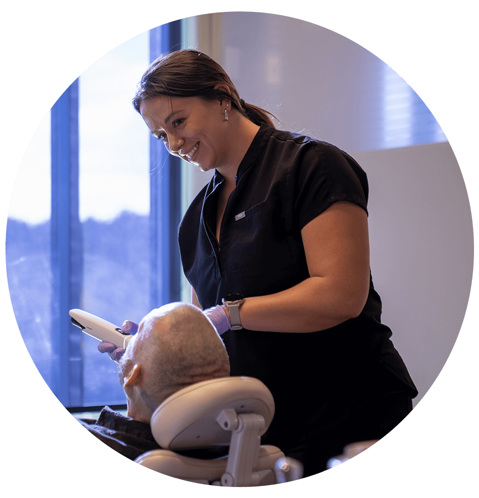 staff member helping with examination of dental implant patient