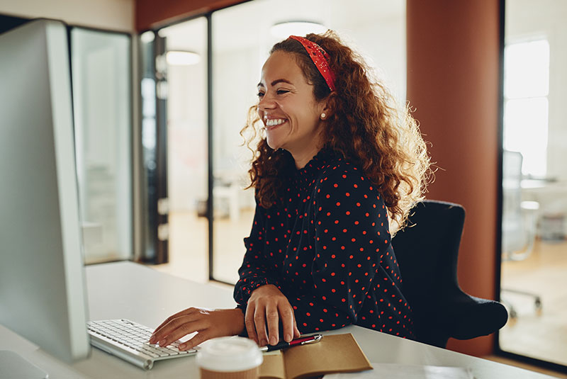 Laughing young businesswoman working on her office computer