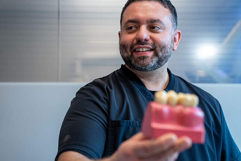 doctor holding a single dental implant model to show to dental implant patient