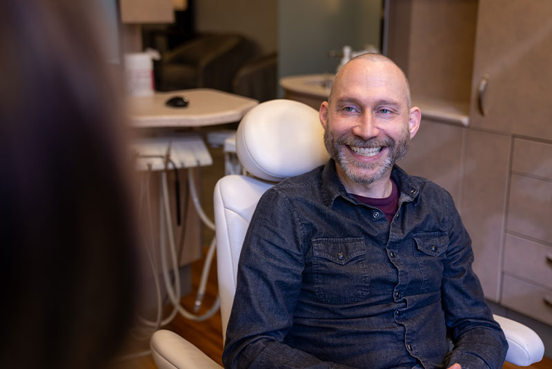 patient smiling brightly while going over dental procedure information with doctor