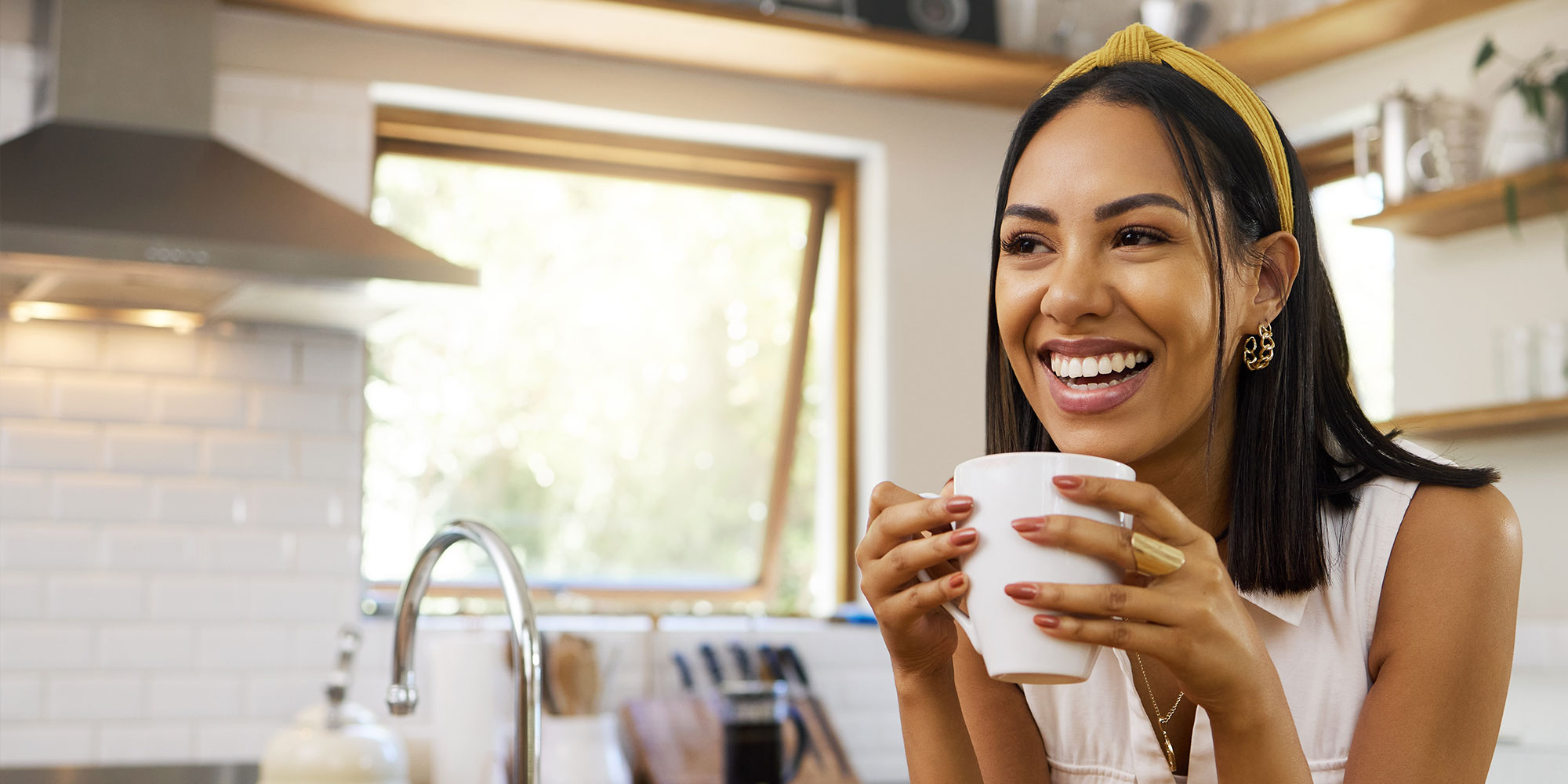Happy woman, coffee or tea in home kitchen and relax with a smile in the morning at house