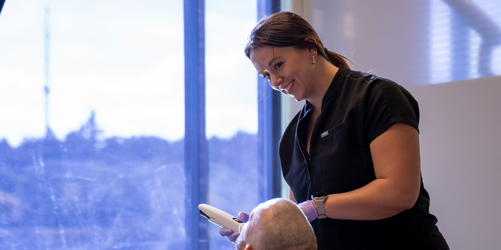 staff member examining dental patient for their impant treatment