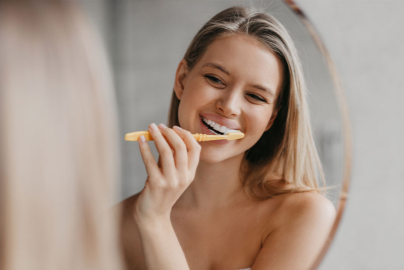 young female brushing their teeth within their bathroom