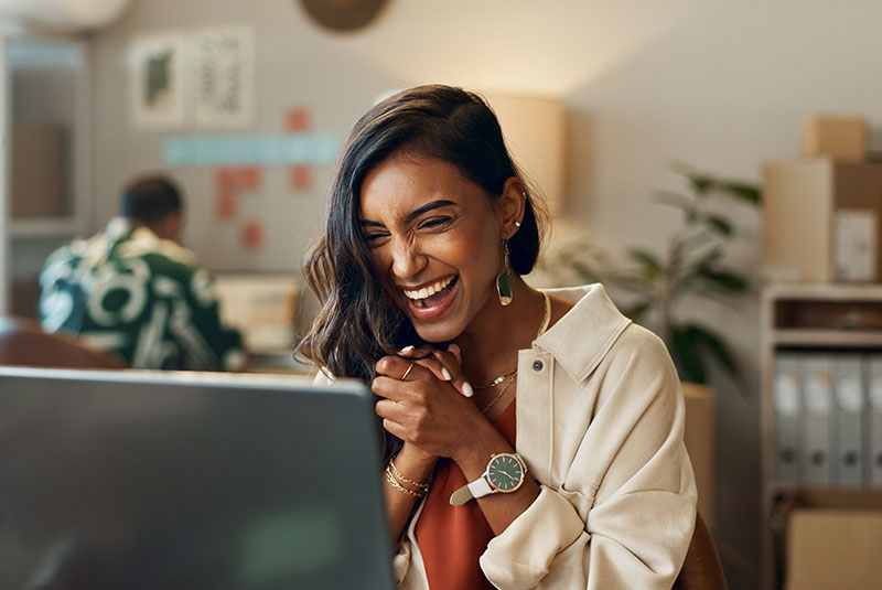 young beautiful female smiling and laughing while on the laptop