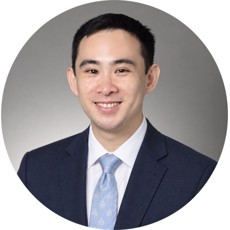 Dr. Burin Thanasuwat, periodontist at Periodontal Associates, smiling in a navy suit and light blue tie.